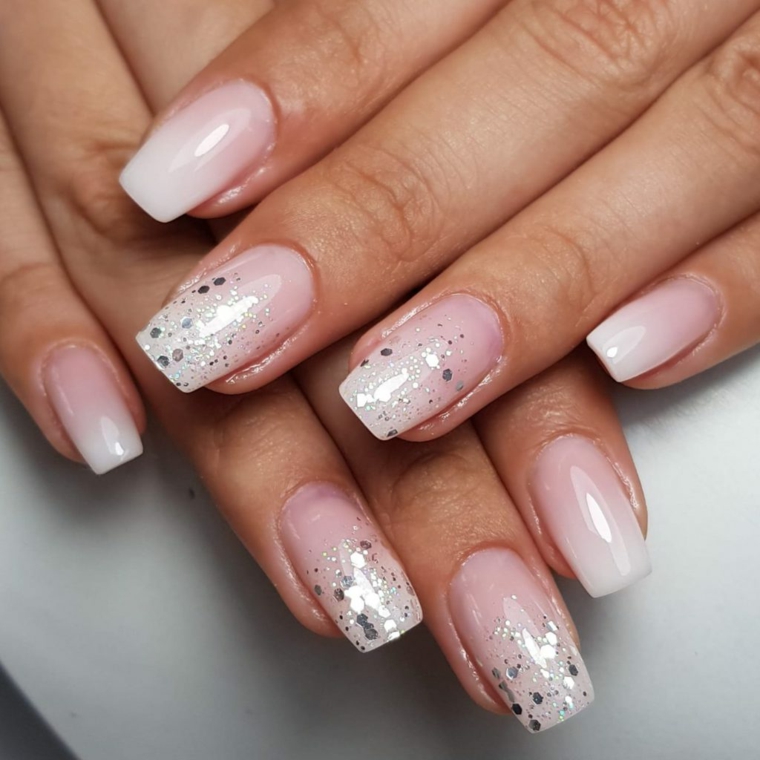 Smalto base di colore rosa, unghie decorate con glitter, mani di una donna