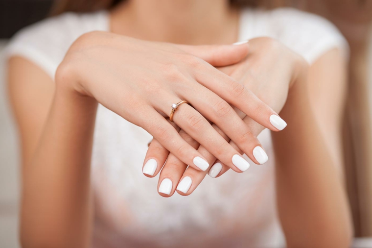 Mani sposa con smalto di colore bianco, unghie bellissime, fede in oro con piccolo diamante 