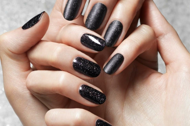 Unghie a mandorla dipinte con uno smalto di colore nero glitter 