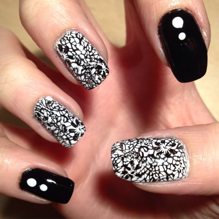 Unghie lunghe di colore nero e accent nail con base smalto bianco e disegni floreali in nero 